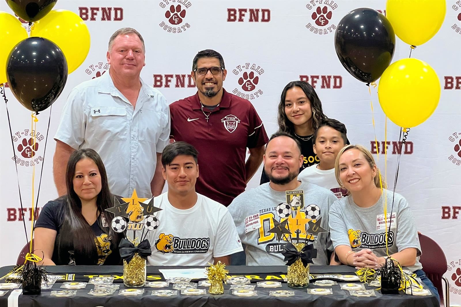 Cy-Fair High School senior Rey Escobar, seated second from left, poses with his family and coaches after signing his letter.